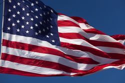 American Flag Waving In Wind Against a Deep Blue Sky.
