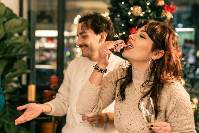 Young woman enjoying a slice of cured meat at a festive Christmas party.