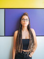 Charming teenage girl with braids in sunglasses nearby colorful wall