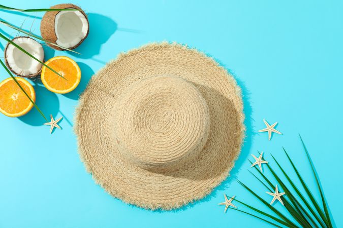 Straw hat, oranges, coconuts, palm leaves and starfishes on color background, space for text and top view. Summer vacation backdrop