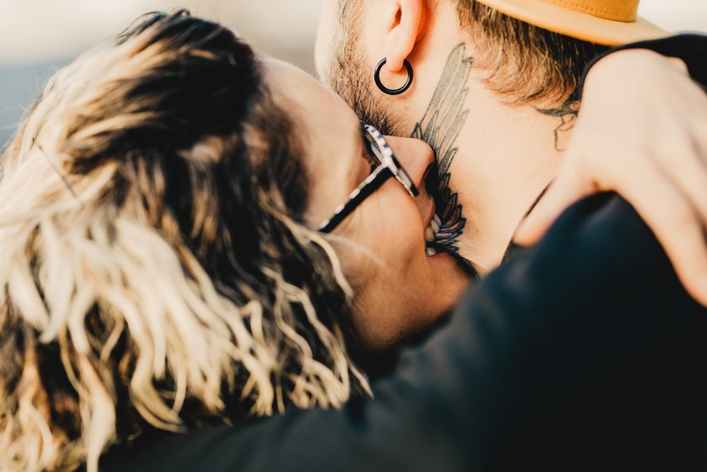 Happy couple hugging and kissing near tree in park