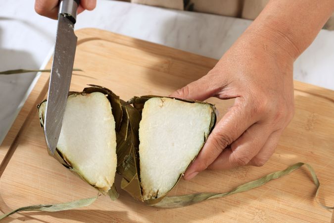 Female Hand Cutting ketupat into Half, Ketupat is Rice Cake with Diamond Shape