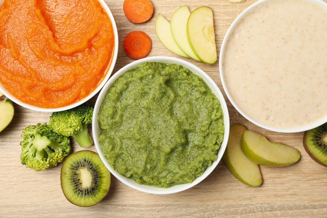 Bowls with vegetable puree on wooden background. Baby food