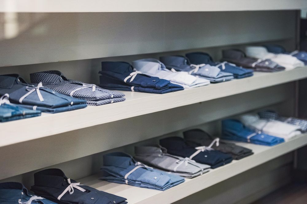 Shelves of folded dress shirts in fashion store
