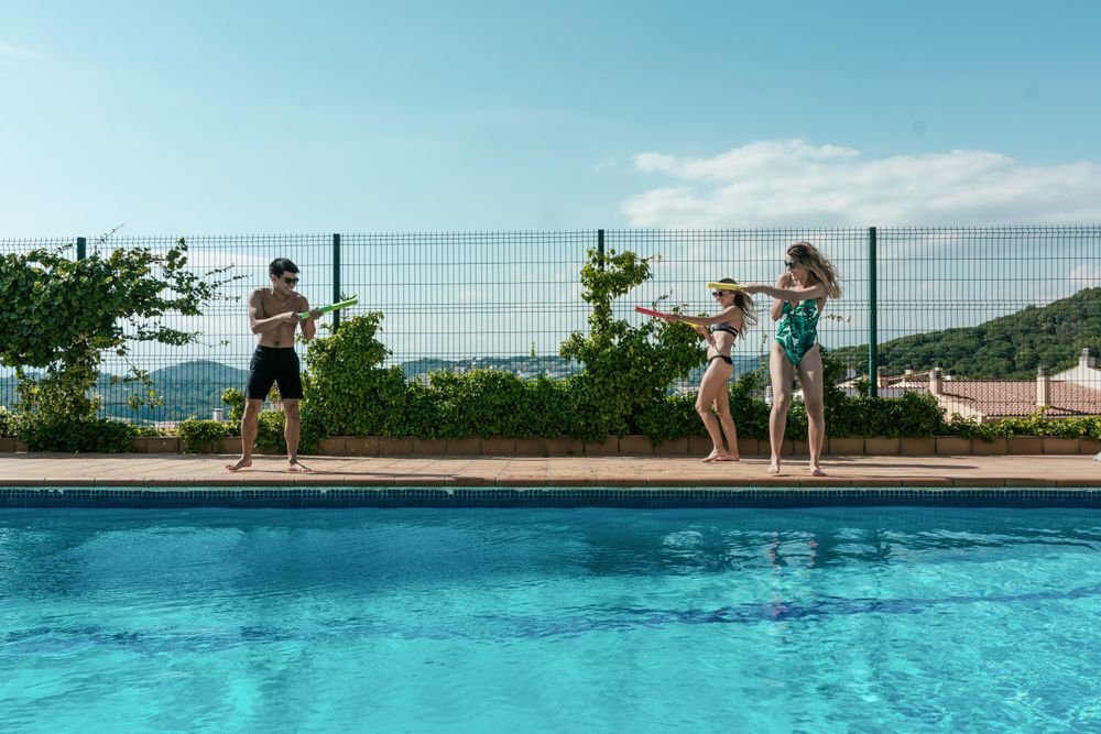 Friends playing with water pistols in the pool