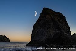 Crescent moon above quiet rocky beach at dusk 0V1RGb