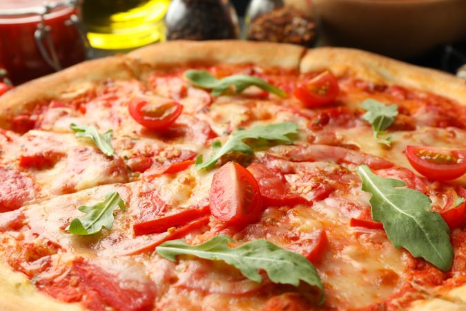 Tasty pizza with tomatoes and arugula leaves, close up