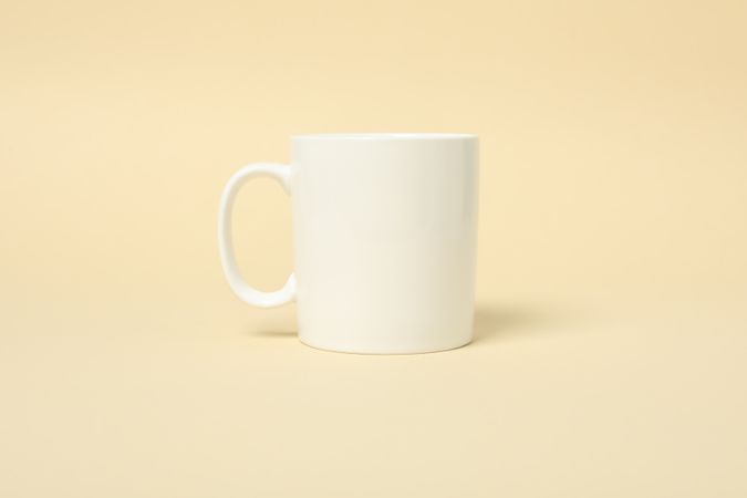 Empty cup on beige background, space for text