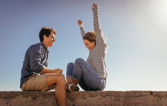 Couple on vacation sitting on a concrete wall on a sunny day