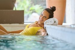 Happy female resting in pool of spa center