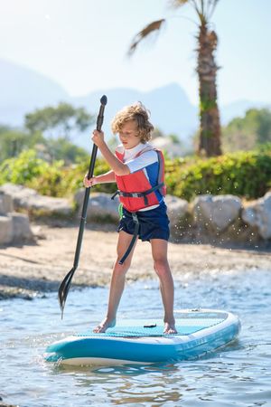 Boy swimming on paddleboard in sea