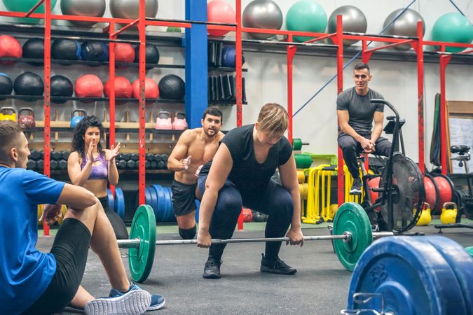 Woman ready to do lifting weights while her gym mates cheering her on