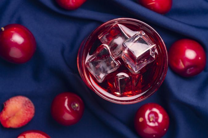 Red beverage near fresh fruits on cloth