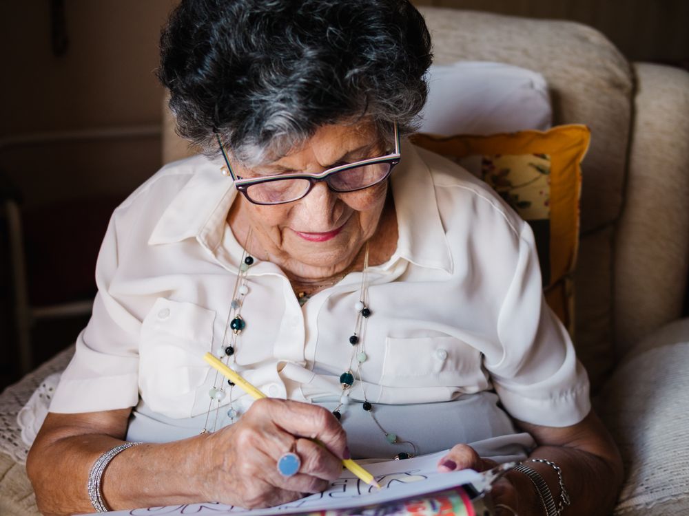 Mature female drawing on paper in apartment
