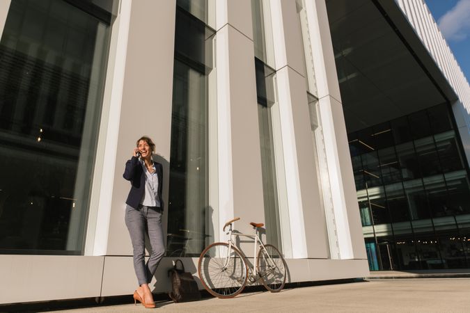 Cheerful female manager speaking on smartphone on street