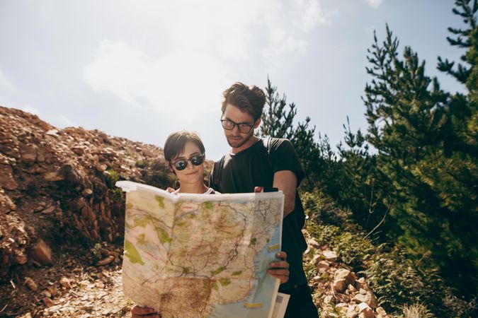 Man and woman holding a navigation map while hiking in a forest