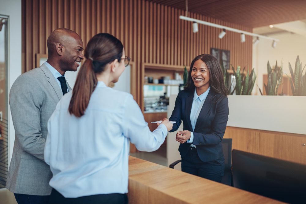 Woman receiving note from two people at the front desk