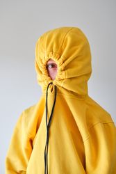 Anonymous child in hoodie against gray wall