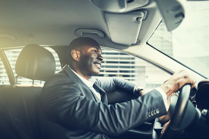 Happy man in business attire driving luxury vehicle