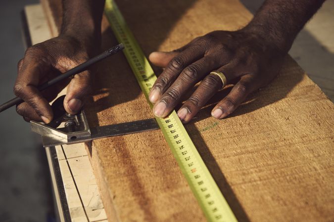 Male hands with measuring tape over wood