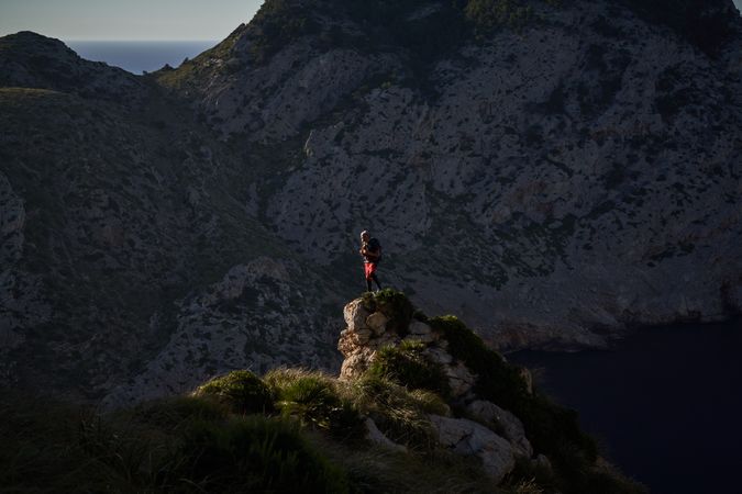 Unrecognizable traveler standing on cliff near ocean