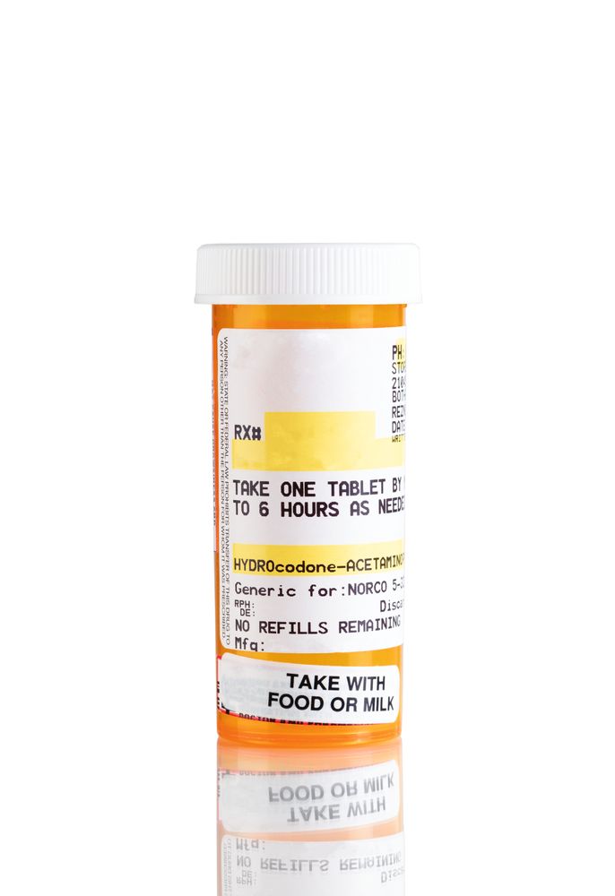 Macro view of opioid tablets in bottle isolated on plain background with reflection