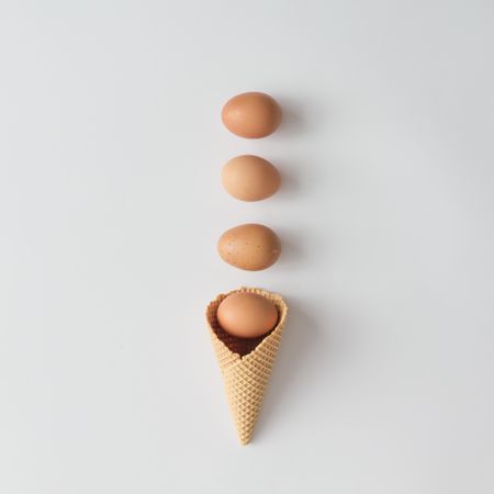 Brown eggs with waffle cone on light background
