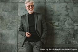Portrait of good looking mature businessman standing relaxed on grey wall 0g7nA0