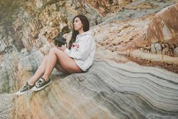 Woman with camera on shore near stones and water