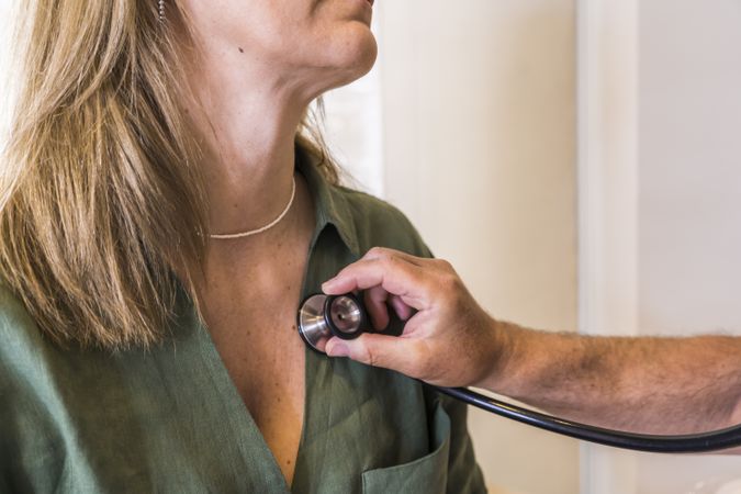 Close-up of a doctor checking her patient's heart beat with stethoscope.