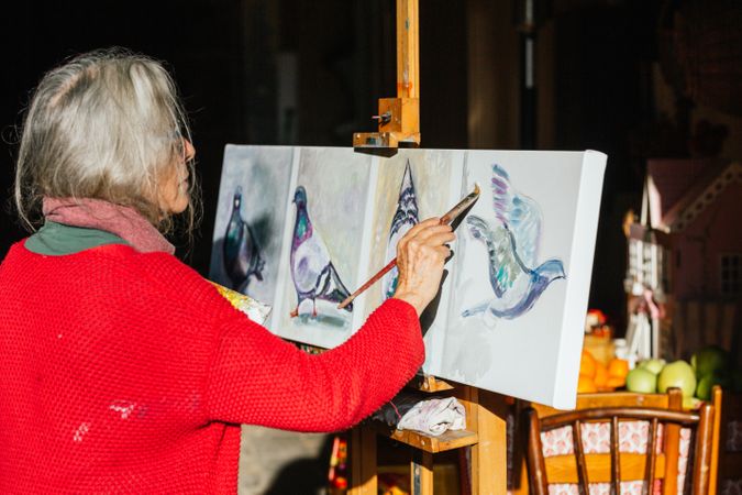 Mature woman painting on canvas in garden