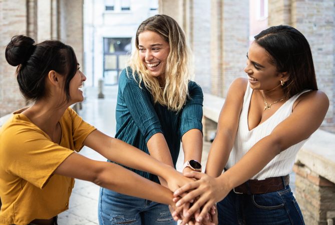 Smiling friends joining their hands together outside in Italian city