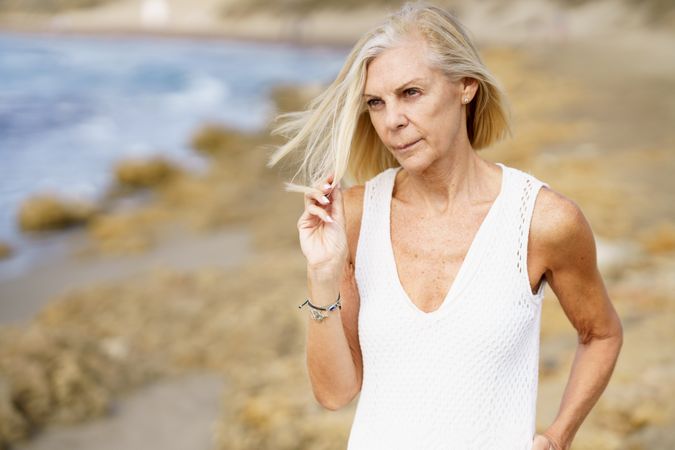 Serious older woman holding hair in consternation on the beach
