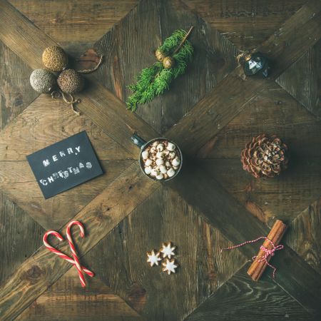 Homely holiday with arranged “Merry Christmas” card, candy canes, hot chocolate, square crop