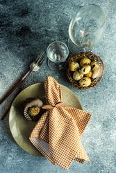 Top view of Easter table setting eggs and checkered napkin