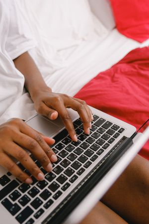 Cropped image of Black person using laptop in bed