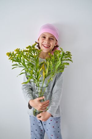 Happy boy in bandana with vase of goldenrods