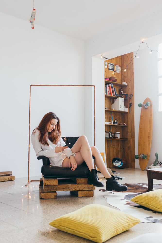 Woman sitting in chair and texting in trendy loft