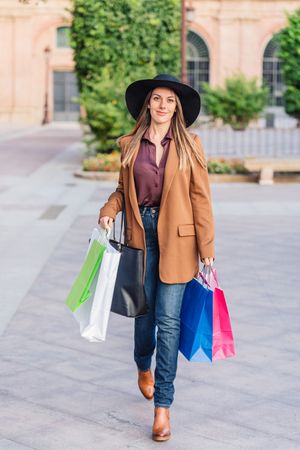 Content female in trendy wear doing shopping at city street