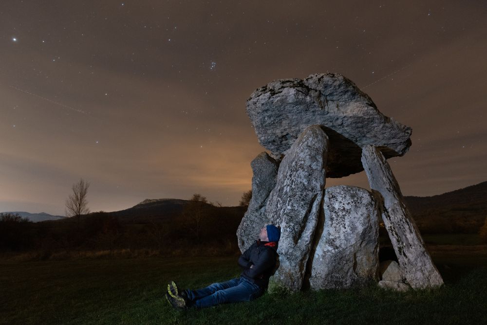 Traveler admiring starry sky near dolmen