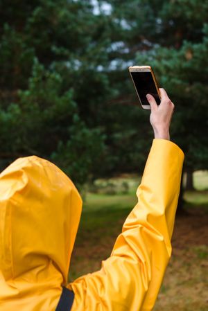 Woman in hoodie and yellow raincoat taking selfie