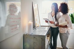 Two women consulting a board in a bright office