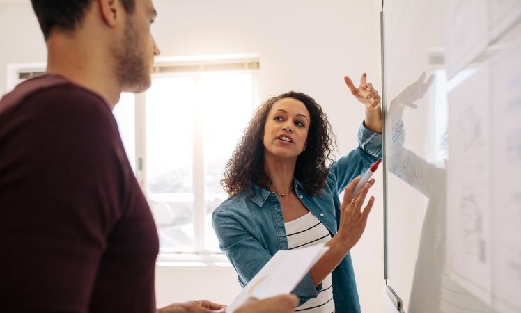 Woman entrepreneur discussing business ideas and plans on a board in office