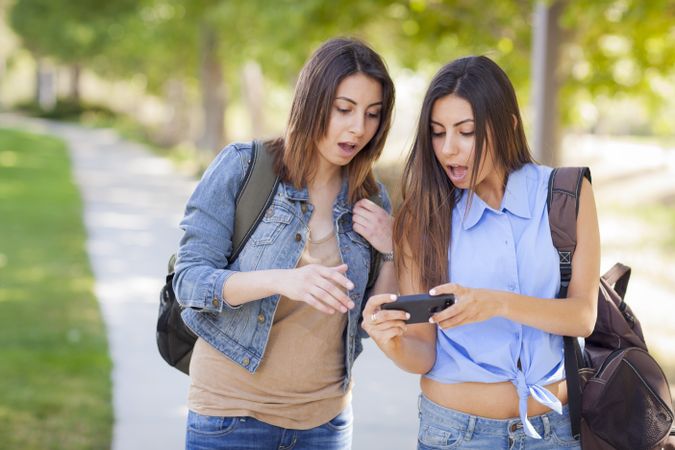 Young Adult Twins Looking Over Phone Screen