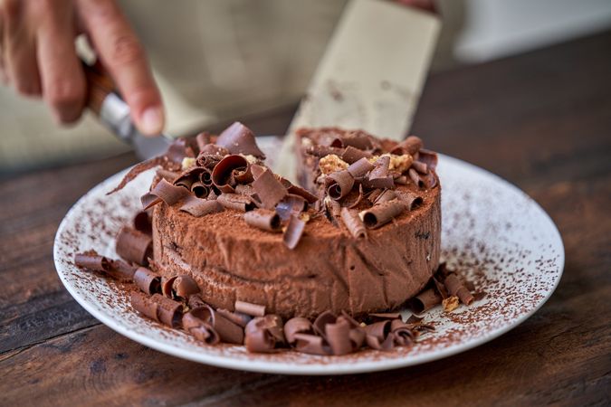 Faceless chef cutting chocolate cake on table