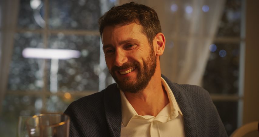 Handsome Man Sitting at a Festive Table with Family and Friends During a Christmas Dinner at Home.
