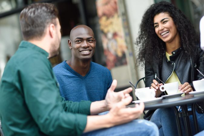 Friends laughing together over a coffee outside