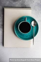 Top view of coffee cup on teal plate and notepad 432QnR
