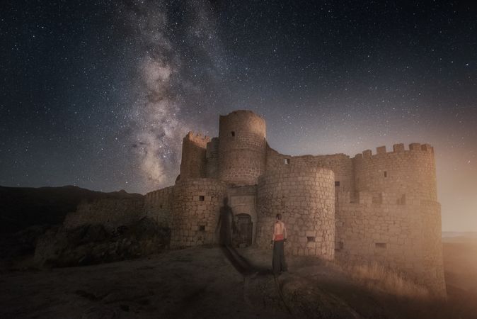 Man beside ruined fort under starry night sky