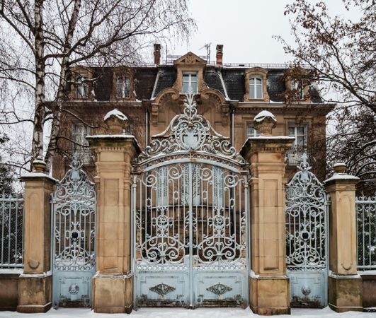 An old manor with beautiful gates is covered with snow.